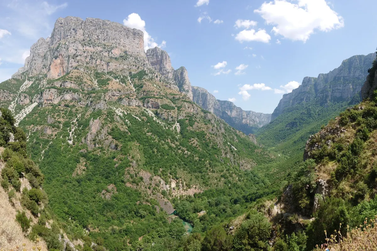 Hluboká zelená soutěska pod vysokými vápenci v soutěsce Vikos, nad ní modrá obloha.